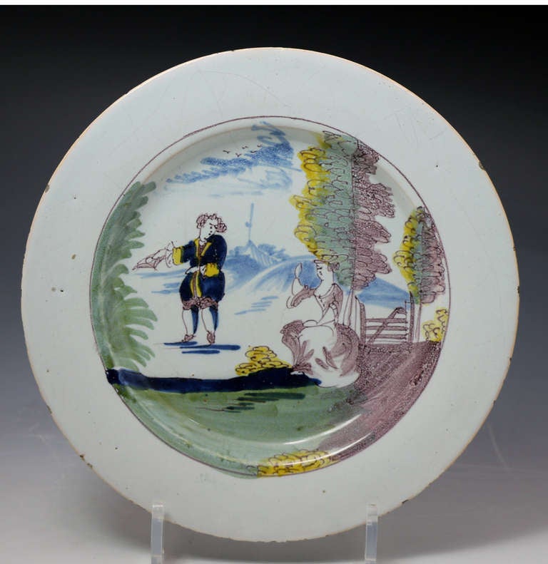 A fine Liverpool Fazackerly delft ware plate in typical palette range of colours. 
The image on the plate depicts the figure of a man doffing his hat to a seated lady who thankfully waives back at him.A rare and unusual piece from the Liverpool