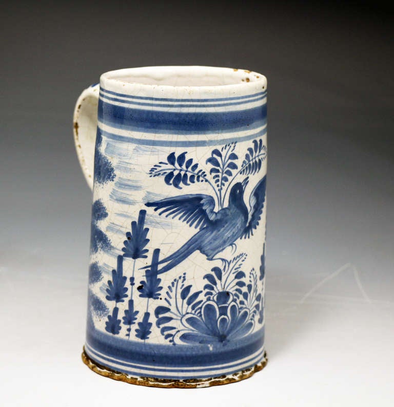 Antique Delft pottery tin glaze tankard decorated vibrantly in blue with a bird and foliage decoration. 
Mid 18th century Holland.