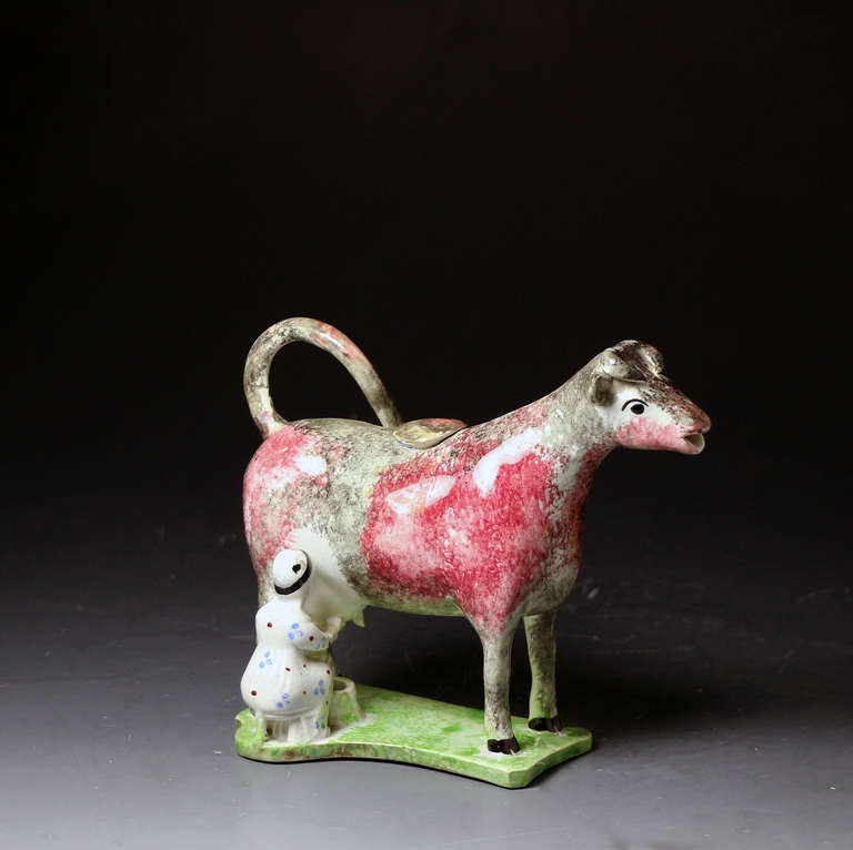 Antique pottery figure of a cow and a milkmaid in the form of a creamer. The coloring and glaze of the figure indicate a North Country pottery manufacture. An interesting feature of the figure is the addition of 