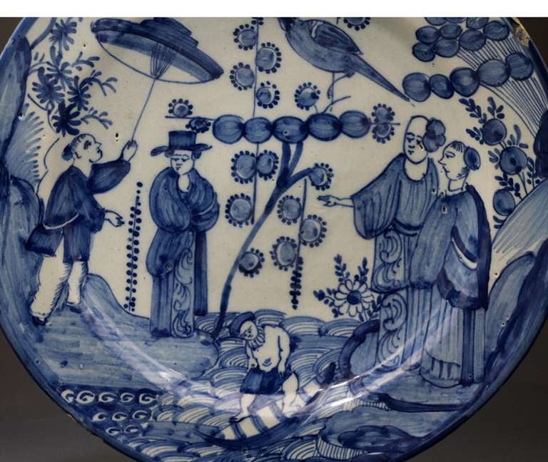 A large and highly decorative Delft dish in blue and white. 
This piece is rare and distinctive in its decoration which features a chinoserie scene with figures covering the entire dish. This borderless feature is most unusual aspect. 
The back of