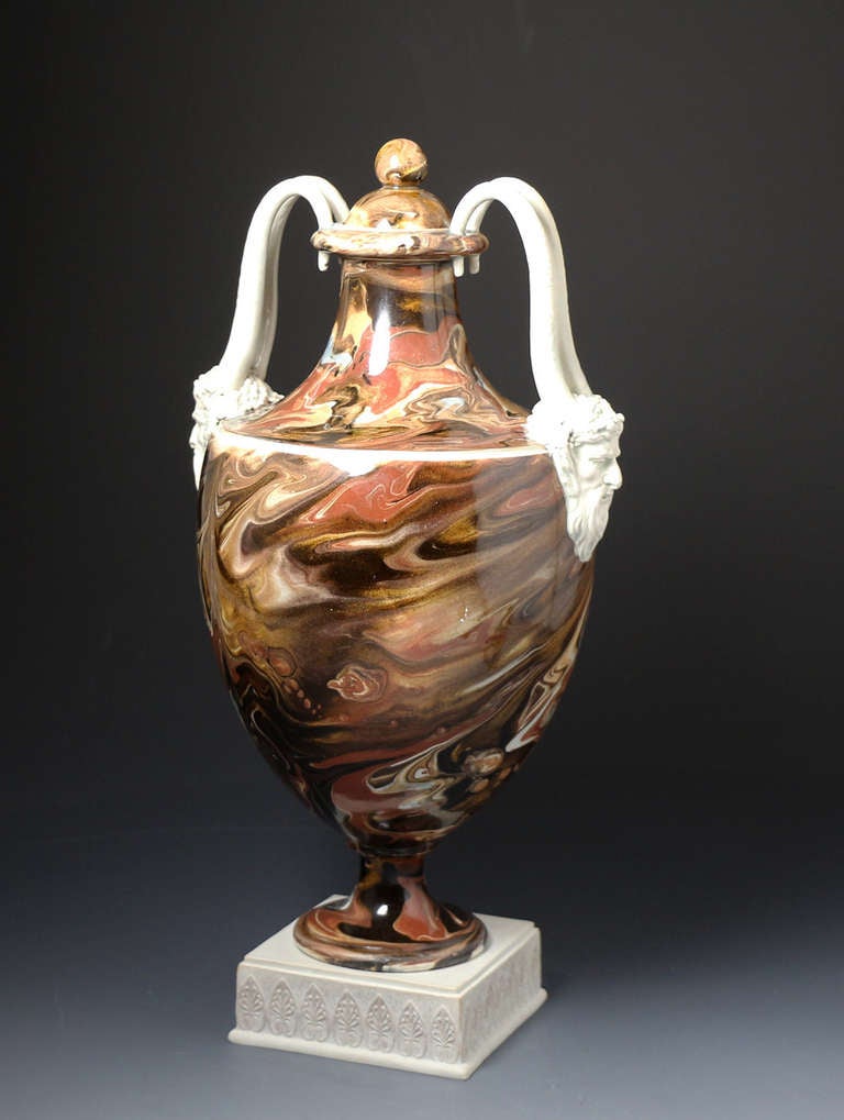 Antique 18th century pottery vase and cover decorated with surface agateware. 
The vase is modeled standing on white basalt plinth which is impressed WEDGWOOD. 
Amphora shaped with an ovoid body and with four striking serpent handles which
