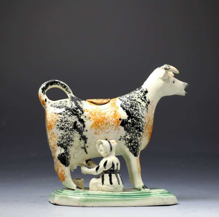 Antique English pottery figure of a cow in the form pof a creamer probably Yorkshire Pottery 

Antique English pottery figure of a cow creamer with milk maid. 
The figure is decorated in the Prattware palette of colors and is modelled standing on