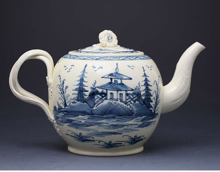English antique creamware pottery teapot in underglaze blue dated 1777 and initialled B.C 
1777 is one of the earliest dates recorded on underglaze blue painted pottery. 
The image of the figure of a woman carrying balance scales is a feature