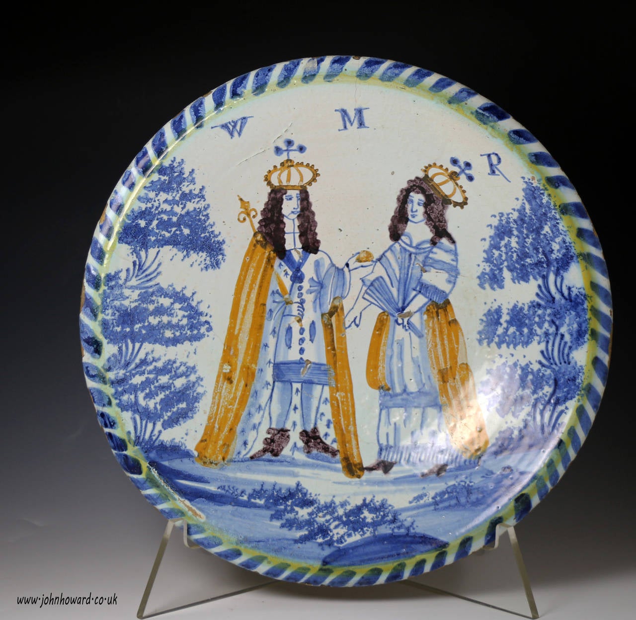 A fine English delftware pottery double Royal portrait of King William and Queen Mary blue dash charger made in c1689-94 period Bristol or London England. 
The monarchs are portrayed with crowns and capes standing between trees with sponged leaves.