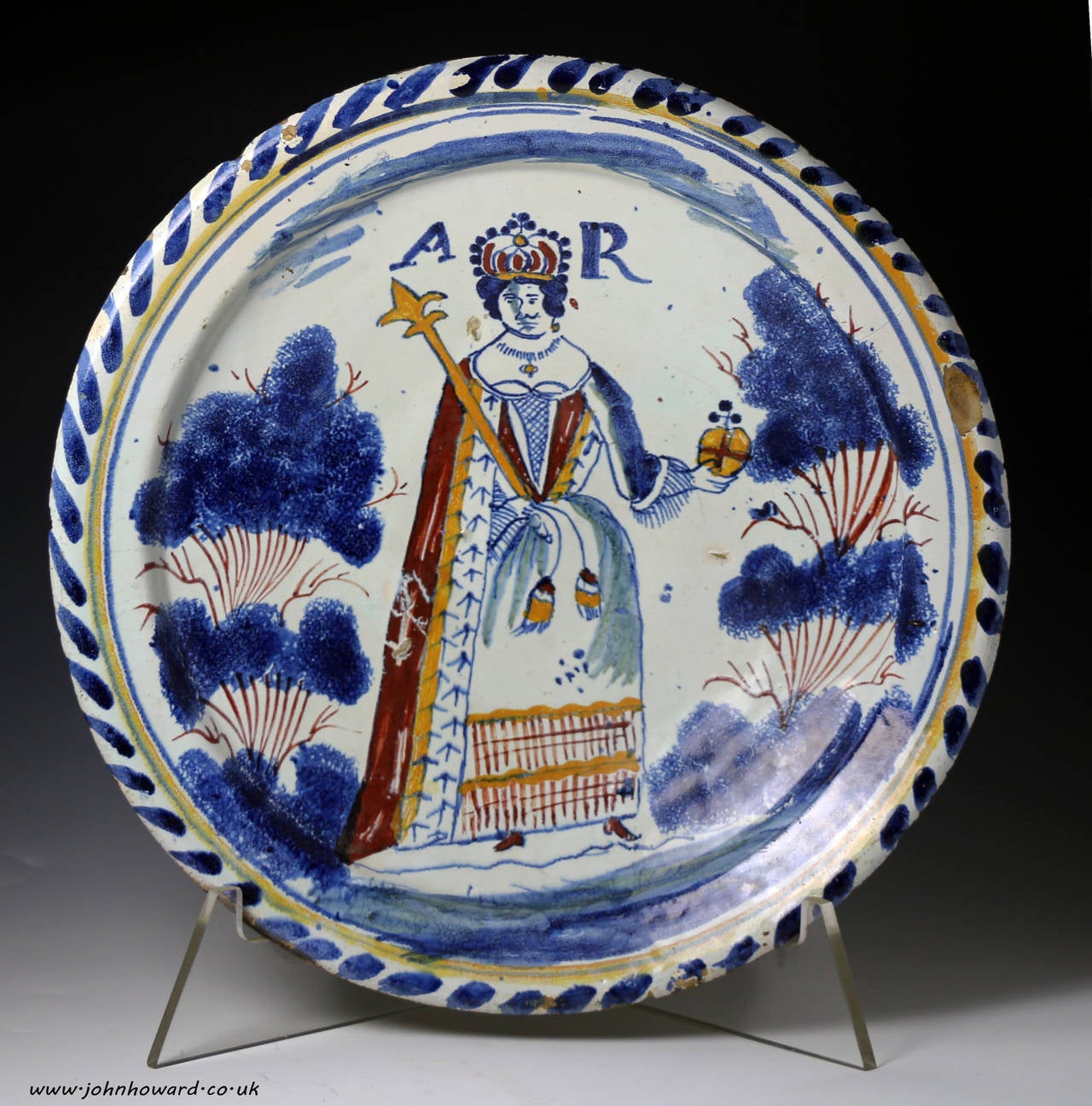 A fine and rare English delftware pottery blue dash charger with the royal portrait of Queen Anne and initials A R. The Queen is crowned and holding an orbe and sceptre.