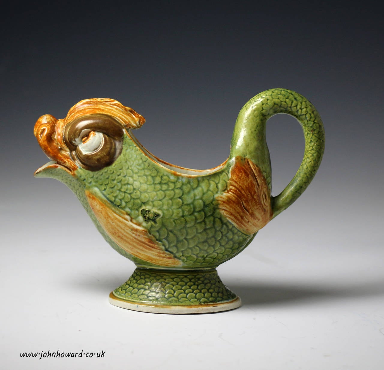 Dolphin shaped pottery sauce boat relief decorated with underglaze Pratt palette colours. 
A good quality example with a touch of the ridiculous denoting a touch of comedy.