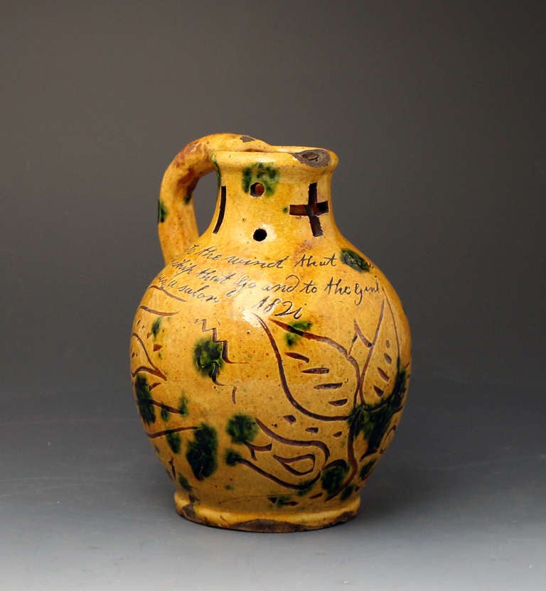A typical example from the Donyatt Pottery of a scraffito decorated puzzle jug with coloured glazes iconically related to the Pottery.The puzzle jug has a sailors poem and is dated 1820. 
Records show that there has been a pottery industry in the