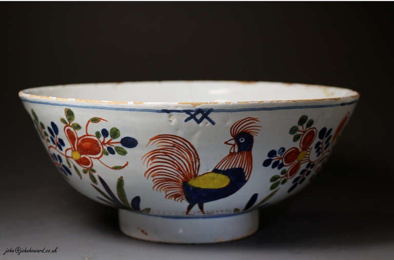 Early 18th century period delft ware bowl decorated with green,red,blue and yellow polychrome colours. The bowl is decorated on the interior with flowers and foliage in blue. 
The outer sides of the bowl feature a fine looking rooster and a beaker