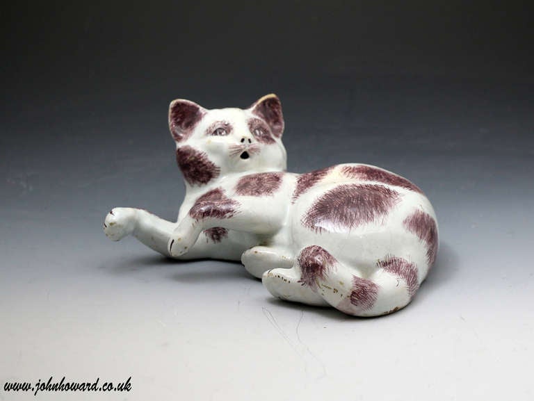 A rare and rather appealing pottery model of a playful cat.
The figure is decorated in manganese colour on a white ground in faience tin glaze.