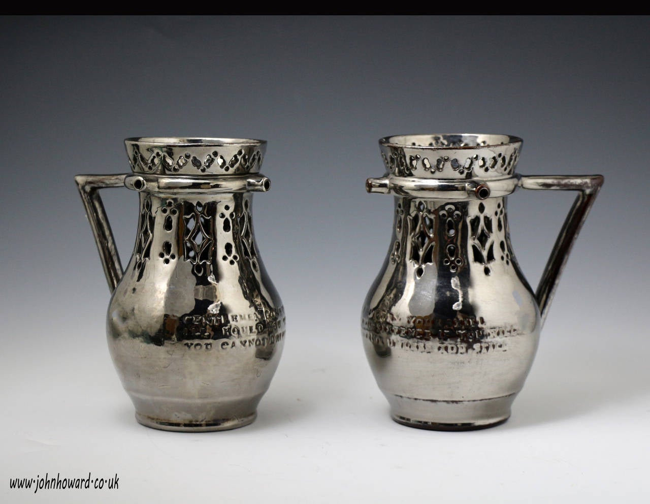 A very rare pair of silver luster puzzle jugs with an impressed inscription challenging to pour without spilling for a wager. 
Early 19th century. 
The two pitchers are in wonderful clean condition with no restorations