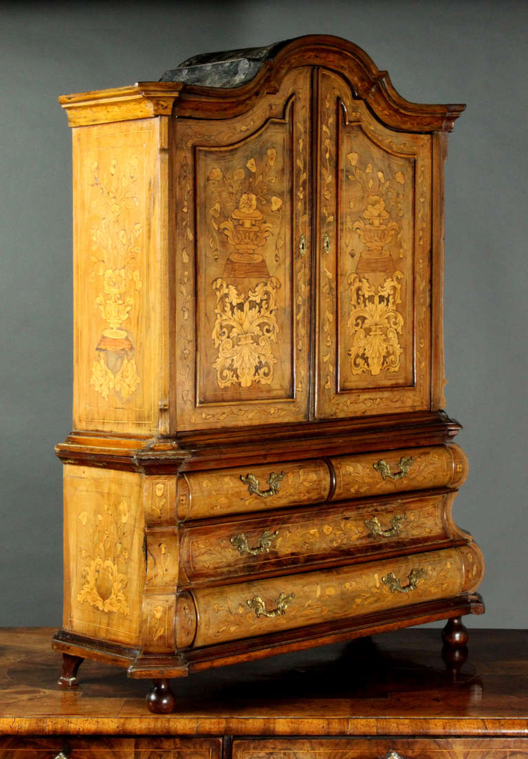 A miniature Dutch floral marquetry press in walnut veneer; as is usual with such pieces the marquetry probably added during the 19th Century; though a pleasing faded colour; the bombe base has canted corners and there are two further