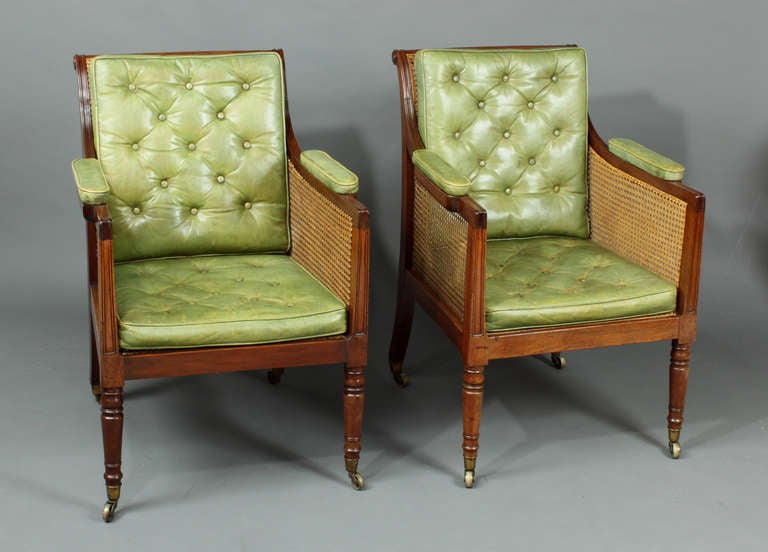 A good pair of Regency mahogany caned bergere chairs with green leather seats.