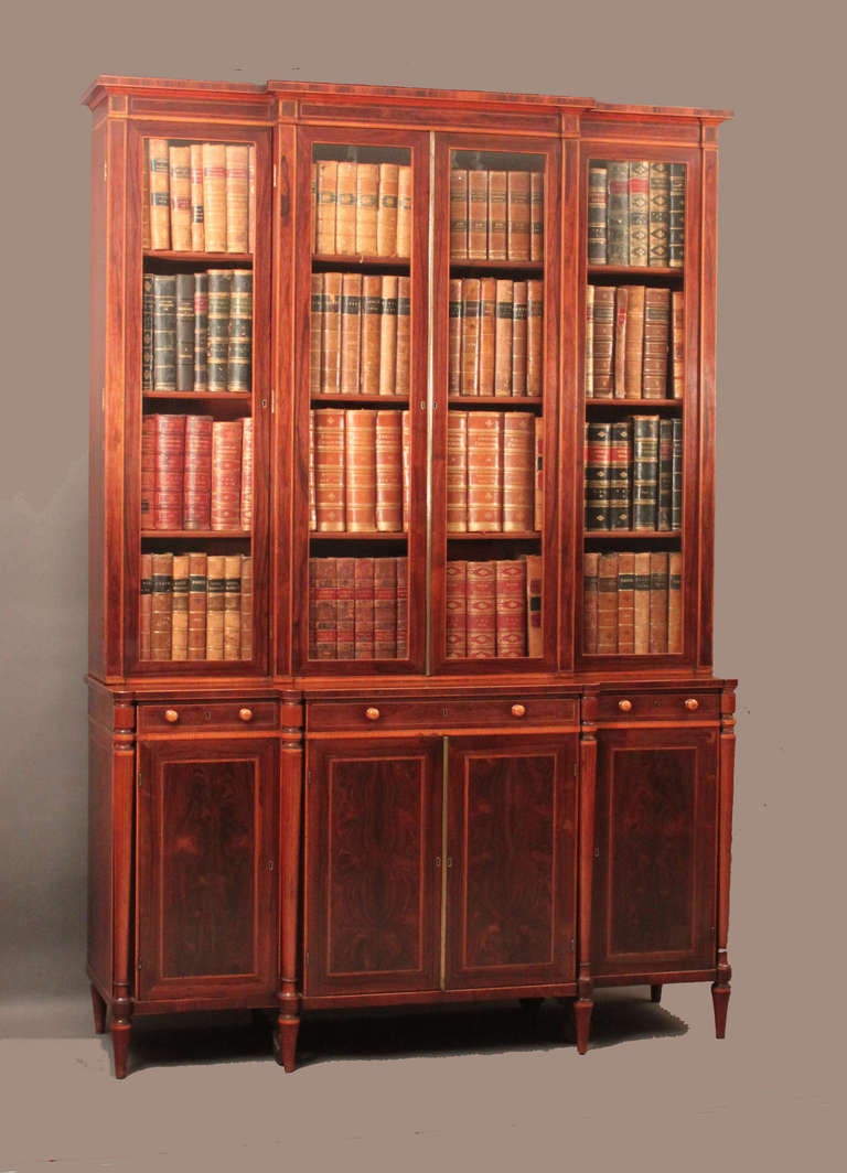 A fine George III breakfront bookcase of compact proportions, attributed to Gillows of Lancaster: in rosewood with boxwood stringing and satinwood banding; attractive turned and tapering column supports. 

The attribution to Gillows is based on