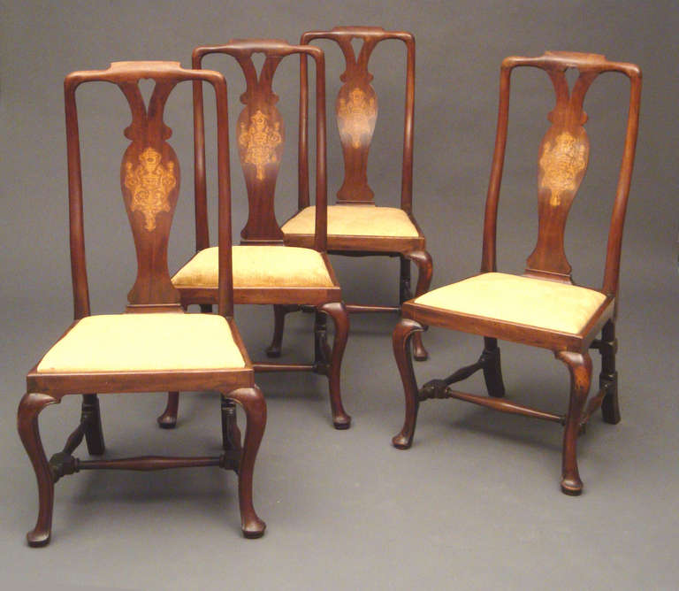 A Set of four George I walnut and marquetry side chairs: the splats inlaid with scallop shell, maskheads and strapwork on carved cabriole legs.
After the ascent of the Hanovarian George I to the English throne in 1714, the influence of European