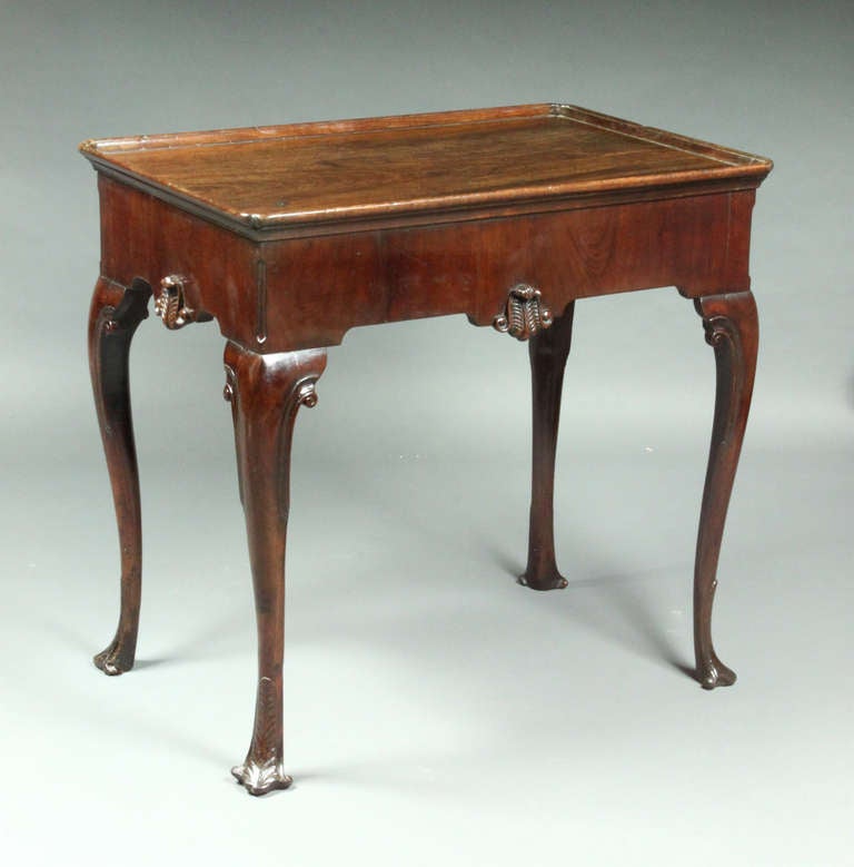 A fine mid 18th Century Irish silver table in mahogany of a good colour and patina; each side with a vertically veneered frieze wand a carved centre motif, the feet also have a similar carved decoration.