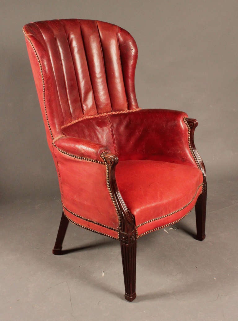 A Mid-19th century mahogany barrel back wing chair in old red leather: stylistically late eighteenth century. Large and very comfortable.