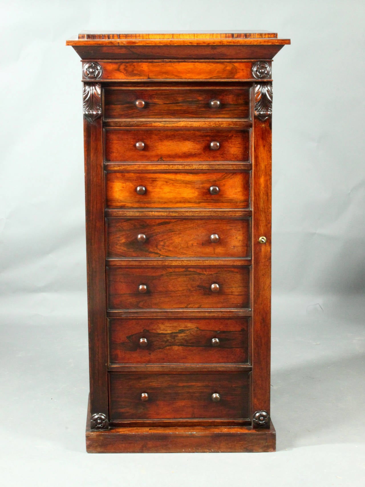 A good quality early 19th Century Wellington chest in rosewood of a good original colour and patina; seven mahogany-lined graduated drawers; well-carved corbels and patera; key