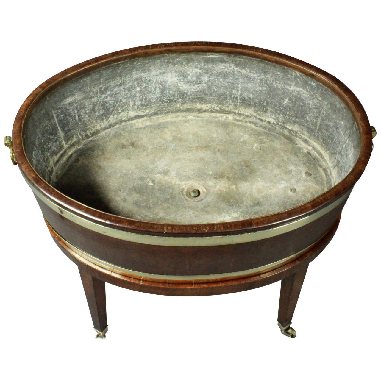 A late 18th Century oval mahogany brass-bound open wine cooler with its original lead lining and plug and on its original stand