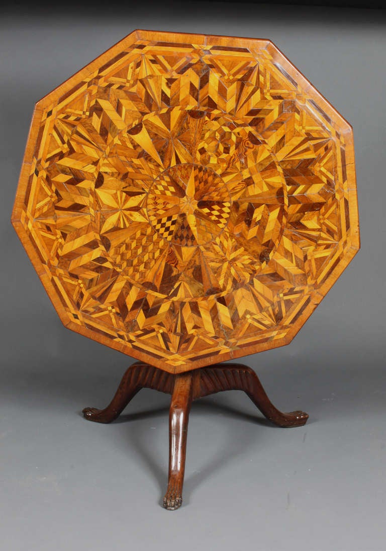 A very unusual Jamaican nine-sided tripod table table made in many different specimen woods; pineapple carved stem and claw feet. Early 19th Century.