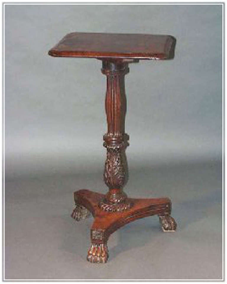 An Indian Colonial occasional table in padouk wood on a carved stem and with three claw feet.