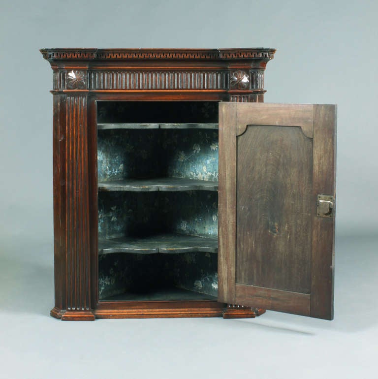 Ein Mahagoni-Eckhängeschrank aus der Zeit von George III. Chippendale mit guter Originalfarbe und -patina; architektonische Details im Gesims mit griechischen Schlüsseldetails, kanneliertem Fries, Pilastern und geschnitzten Blumenpateren; gewölbte