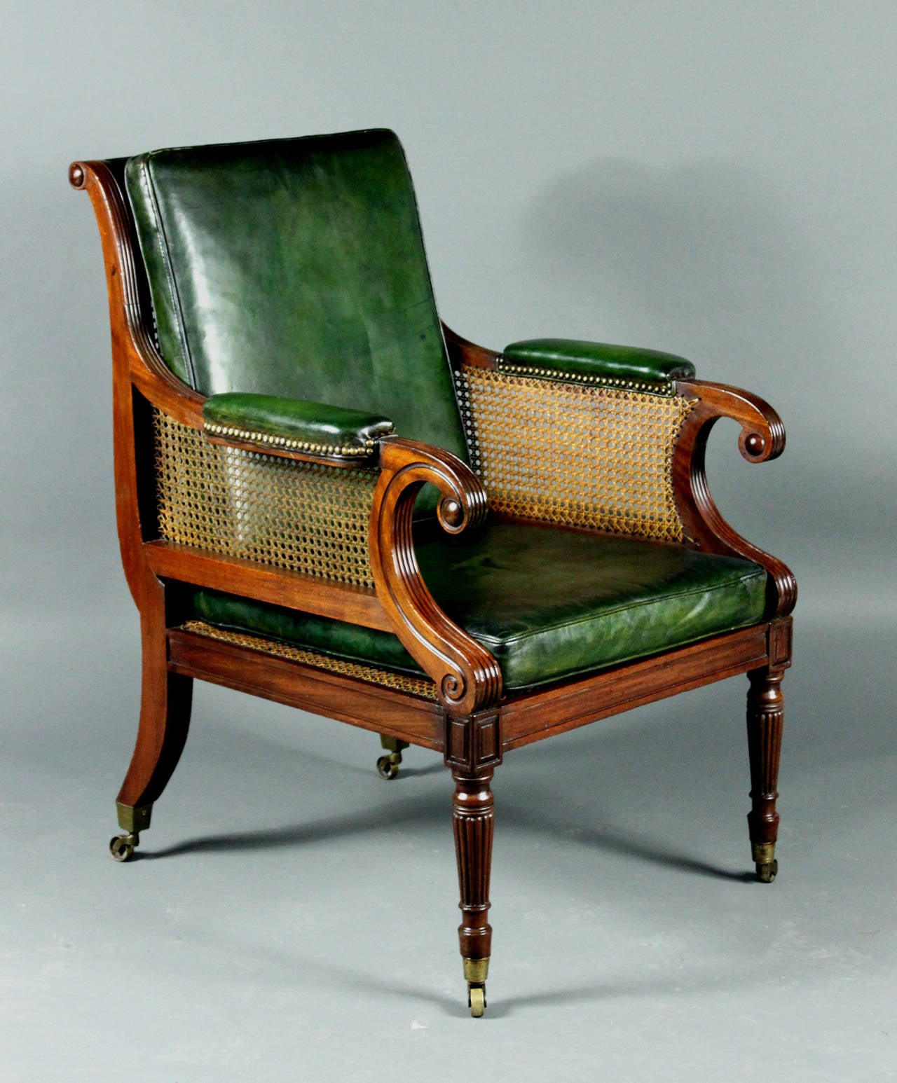 A fine Regency mahogany bergere chair with handsome scroll arm and reeding to the legs, arms and back