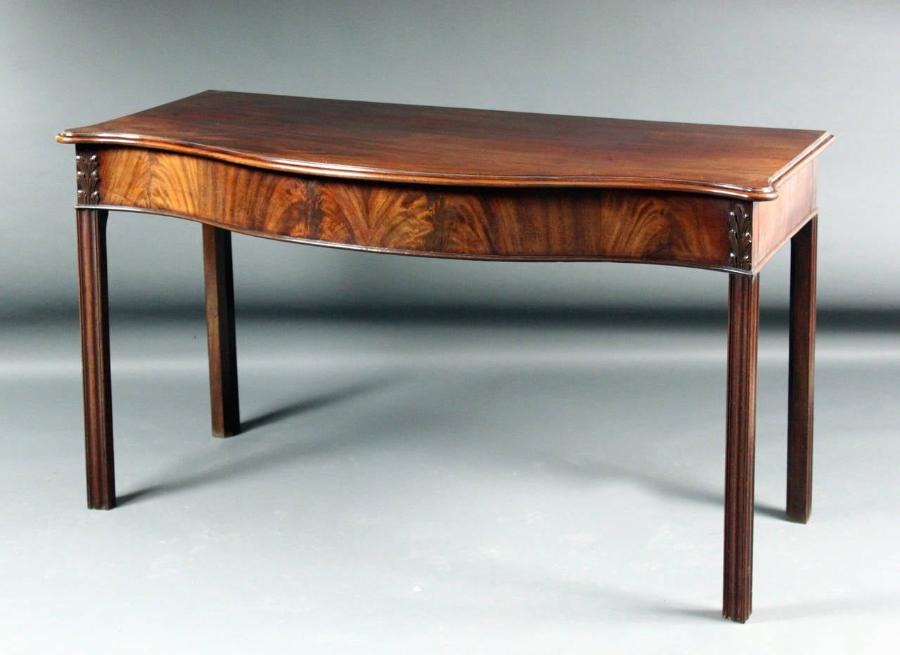 A George III Chippendale period mahogany serpentine-front side table of a good original color and patina: the carved acanthus leaves at the top of the legs is a rare feature.