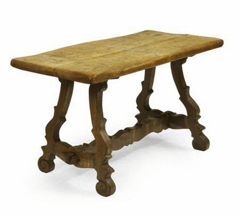 An oak table in the manner of Sir Robert Lorimer, the rectangular adzed top above scrolling legs joined by a pegged scrolling stretcher. 