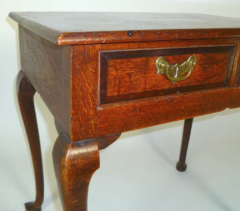 A George III oak low boy fitted with two mahogany cross banded short drawers on cabriole legs and pointed pad feet
