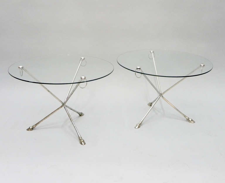 Pair of round glass and nickel side tables with horse shoe detail and nickel rings.