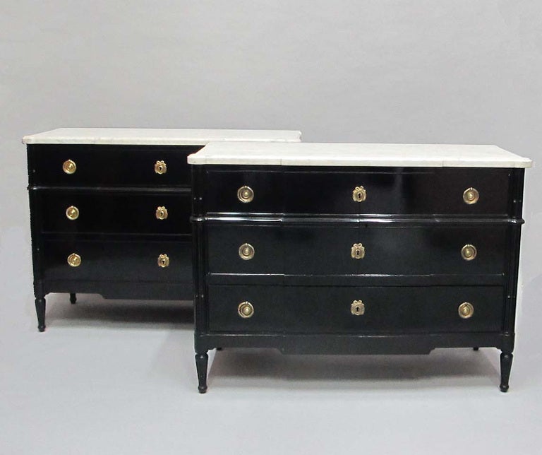 Fine ebonised French Directoire Style commodes with original white marble tops, stamped Jansen. Made specifically for a palacial residence in Buenos Aires. One of the commodes opens as a cabinet with a bottom drawer.
