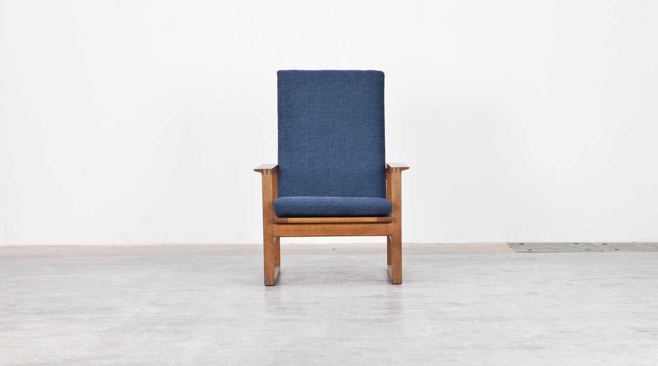 Børge Mogensen lounge chair with matching ottoman in oak is new upholstered and features a high slatted back which makes a very comfortable seating experience. Nice leather strings on the brass pins are holding the seat cushions in position.