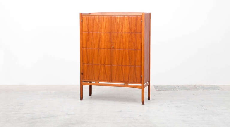 Teak cabinet designed by Yngve Ekström for Westbergs Moebler.
Two beautiful teak doors with milled relief decor, interior with pullout trays and shelves. Teak-capped legs and oak frame.