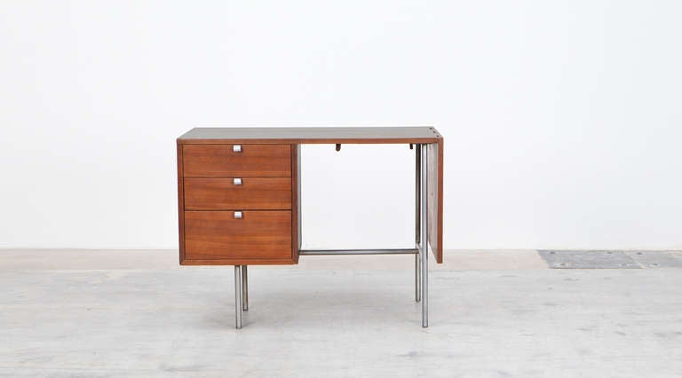 Extendable writing desk out of walnut wood. Chromium plated steel feet.<br />
Designed by George Nelson. Produced by Herman Miller.