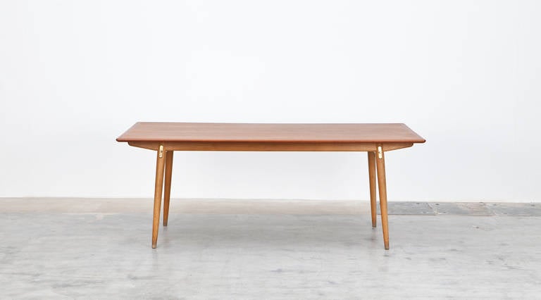 Stunning, solid dining table designed by Hans Wegner comes with a teak top on four oak legs and frame. The table is extendable to a maximum length of 297 cm. The details for that are in metal and brass. Manufactured by Johannes Hansen.

1936-38