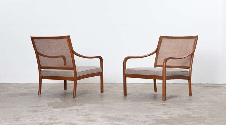 The Pair of Mid-Century Lounge Chairs are walnut. The seat is reupholstered with high-quality fabric and the backrest is nicely woven from where two elegantly curved armrests appear. The wood is reworked. Manufactured by Drexel.