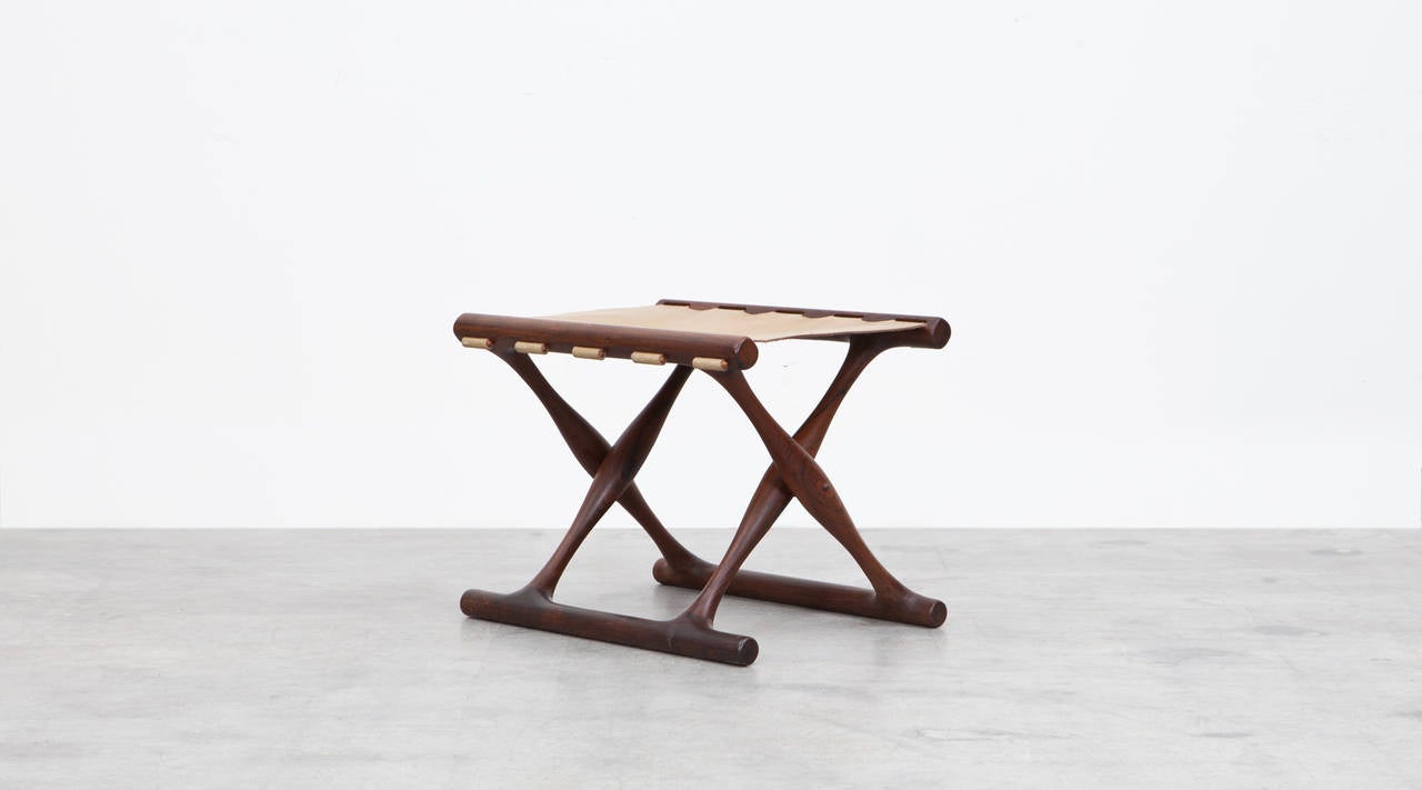 Folding stool designed by Poul Hundevad made out of wood and thick leather. The leather seat is skillful incorporated in the wooden base and lends great contrast to the dark frame. Manufactured by Vamdrup.