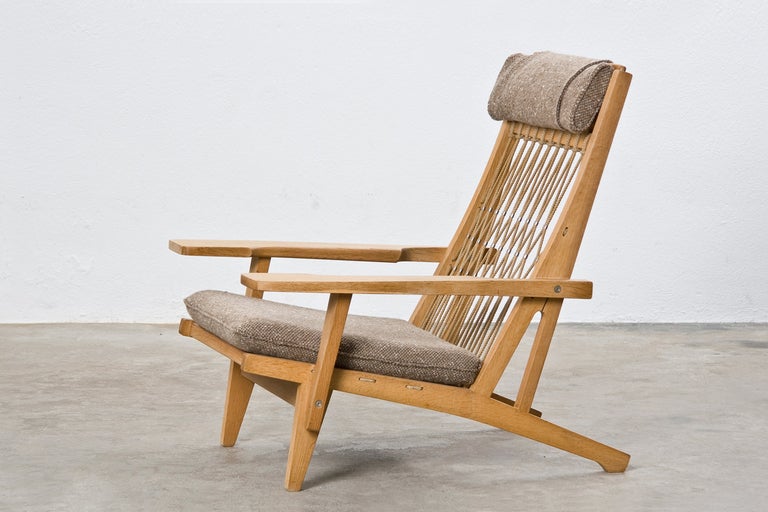 Danish Modern lounge chair designed by Hans Wegner for Johannes Hansen with a harmonious mix of different materials such as oak wood, knotted naval rope back, upholstered seat cushion and headrest.