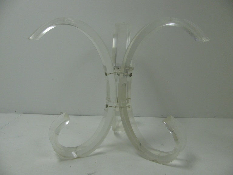Fantastic Lucite table base styled after a fleur-de-leis. Flat bands of Lucite which supports beveled glass top. At the base Lucite has a more severe arc which curls back towards centre. Outer edge of all Lucite is beveled. Measure: Base could