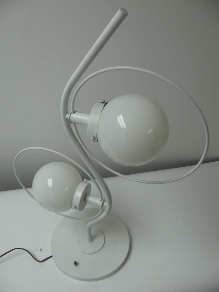Pair of 1960s white lacquered lamps. Tall, sculptural lamps with a three way switch that powers opaque globes. Brass frames. This item can be parcel posted.