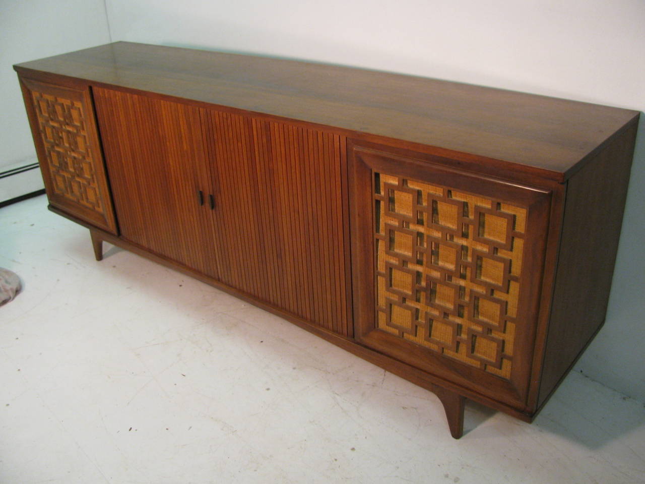 Beautiful large seven foot credenza, created from walnut with a centered pair of tambour doors. Credenza has one large door at the corners which open straight out. Adequate shelving is original. All inquiries please call or just press 
