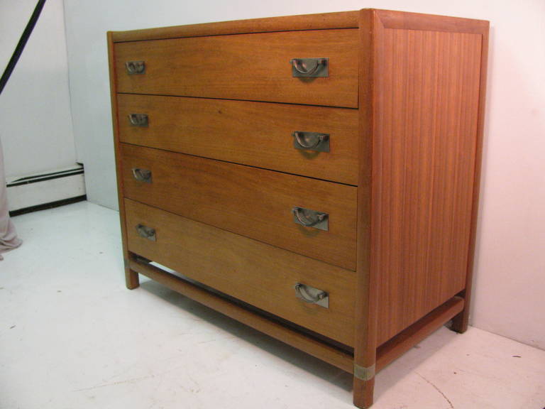 Exceptional matched pair of four-drawer chests. Created out of teak and in very good condition. Stretcher connects legs to sides and front with a stainless band.