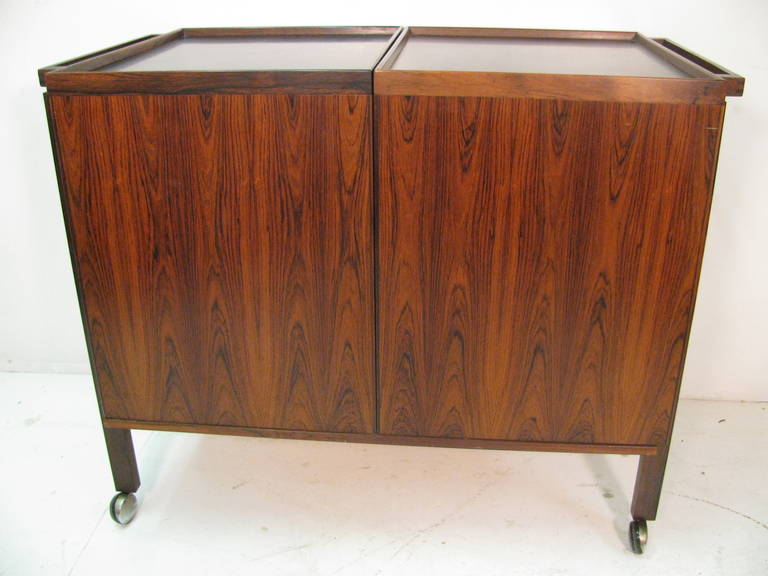 Beautiful And Elegant Book Matched Rosewood Bar Cart. Danish Design Which Opens To Reveal Glass Shelf And Doors for Separation Of Bottles, Glasses, Etc.  When Fully Open Length Is 56in.  Laminate Top For Protection When Serving.