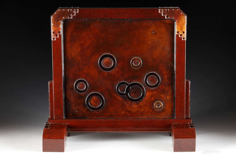 Kenbyo or table screen with an angular, Art Deco style frame, ornamented on the front with circular, stylized bubbles; and on the reverse with a modernist design of an angler fish framed by a band of stylized waves. The frame of red-brown lacquer,