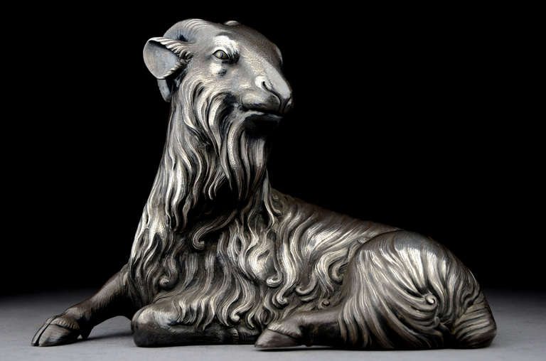 Okimono or sculpture in the form of a seated yagi or goat. Of cast and cold chiseled silver, the eyes inlaid in shakudö and gold. Signed on the reverse with a chiseled signature by the artist: Bisei, and with a kakihan (Unno Bisei, the go or art