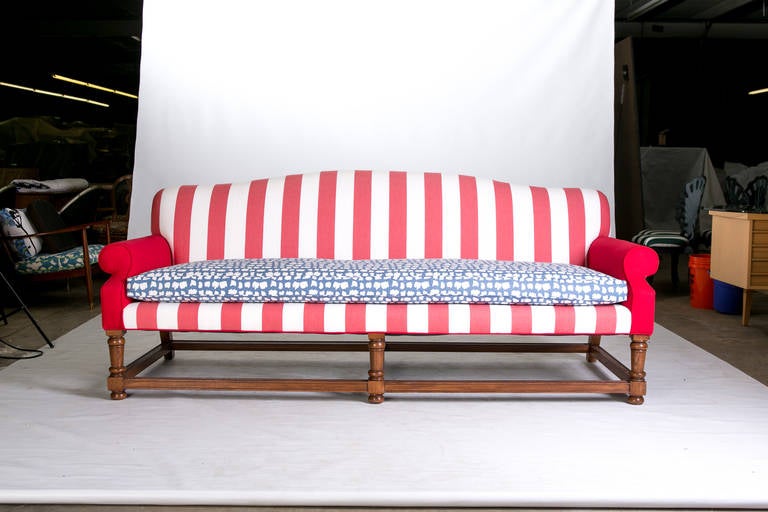 A generously proportioned English camelback sofa upholstered in a show-stopping red-and-white stripe with blue-and-white down-and-feather bench cushion. The sofa frame is vintage. The upholstery is new. The bench cushion has clips to hold the ends