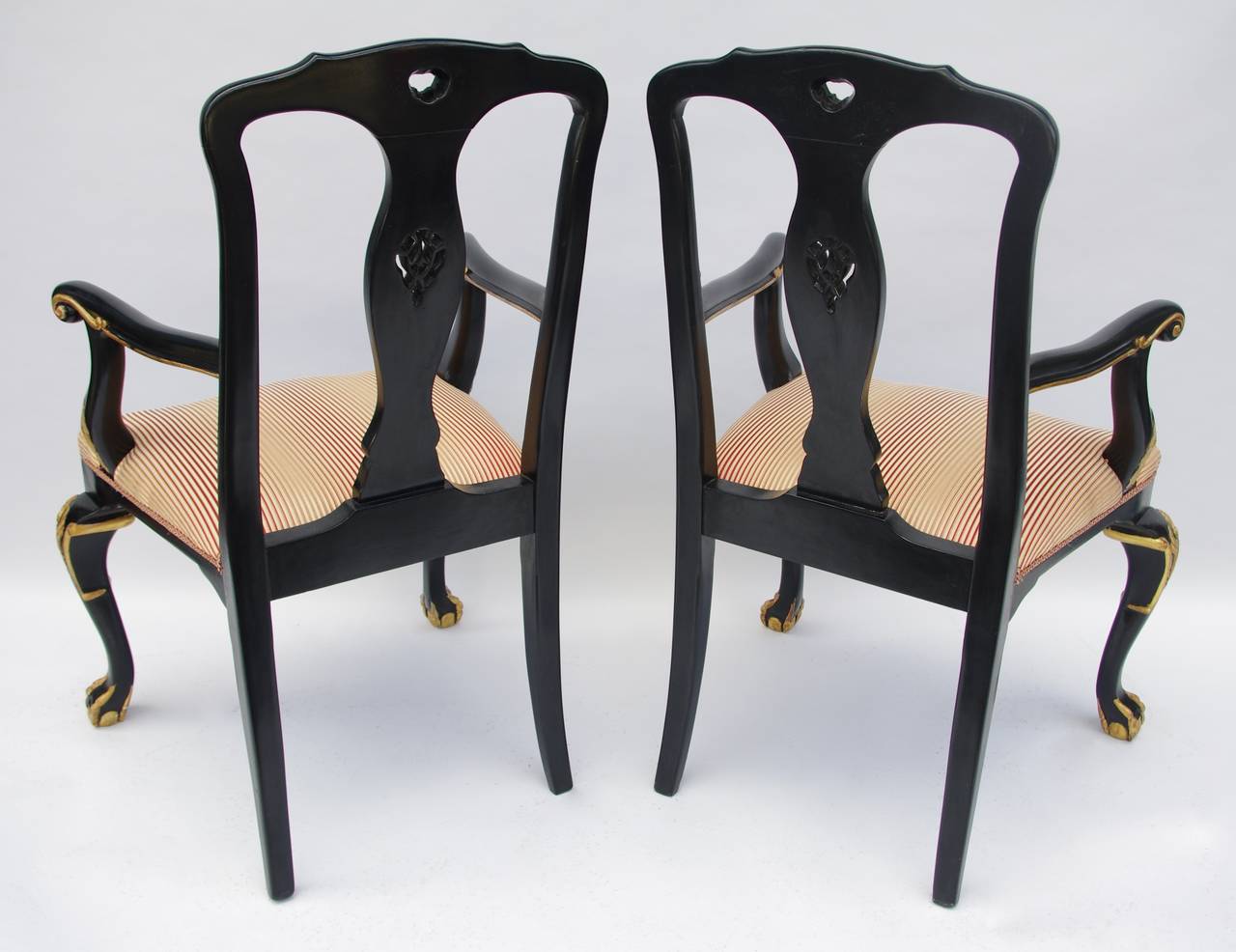 Zwei geschnitzte und schwarz lackierte Holzsessel im Chippendale-Stil, die auf zwei hinteren Säbelbeinen und zwei vorderen Klauen- und Kugelbeinen stehen, charakteristisch für den Chippendale-Stil. Rechteckige und durchbrochene Rückenlehne mit