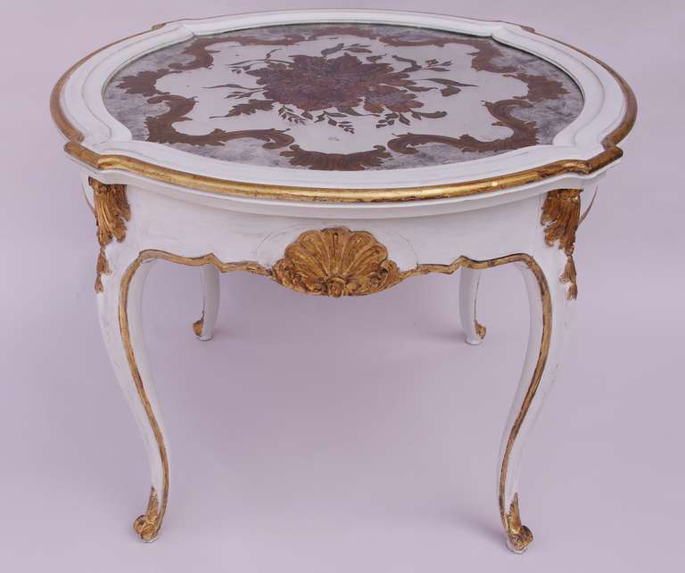 . White lacquered
. Gilt parts
. French work from 1950
. Églomisé glass top
. Louis XV style.