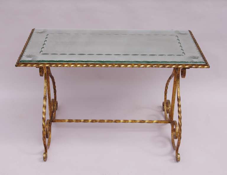 Coffee table with a gilt wrought iron base and a notched, frosted and engraved glass top.
Work from the 1950’s.