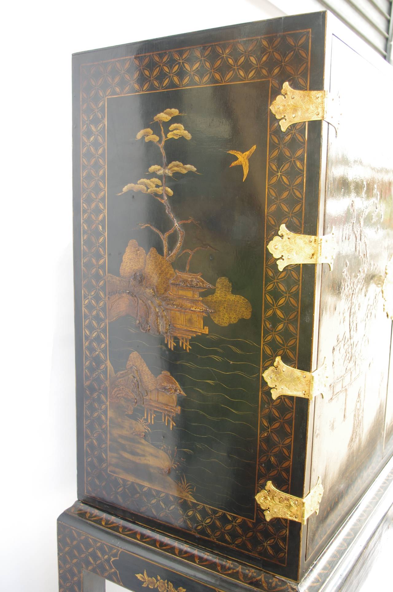 . Chinese style lacquer
. Gilt decor on black background of landscape scenes
. Gilt and chiseled bronze such as : keyhole 
. Circa 1900
. Opening on 2 doors revealing a red lacquer decor background with 7 drawers and 2 doors
. Standing on four